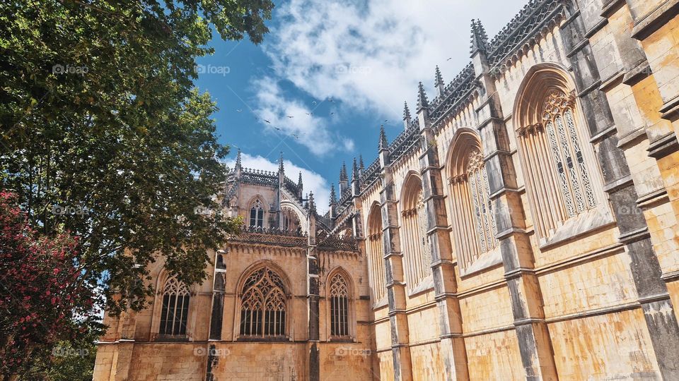 Batalha, Portugal - September 1, 2024: The Batalha Monastery, a stunning example of Gothic architecture, stands majestically under a bright blue sky. This UNESCO World Heritage site is renowned for its intricate design and historical significance.