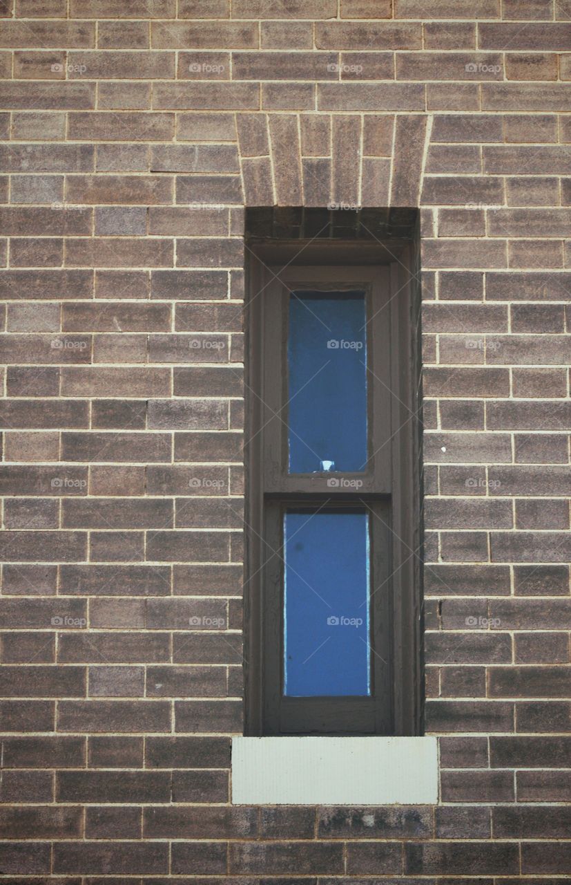 A narrow window with painted trim in an historical brick building 