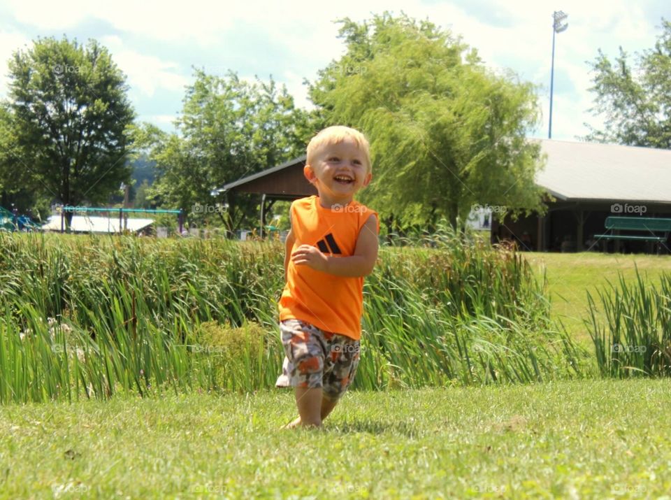 Happy cute boy walking on grass at farm