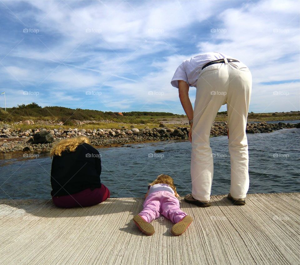 Crabfishing. Little girl laying on her stomach on the jetty