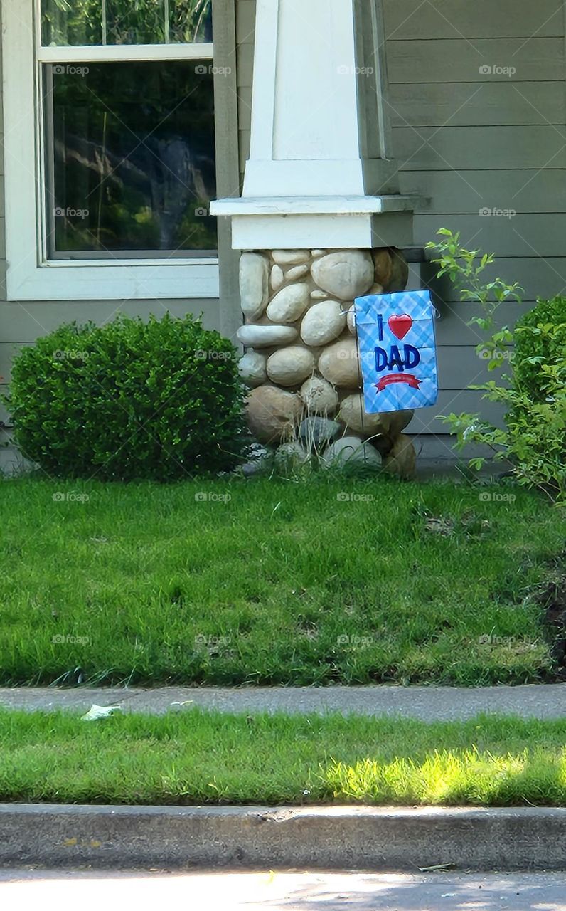 blue sign attached to stone column on house in suburban neighborhood celebrating the loving relationship between a father and their children