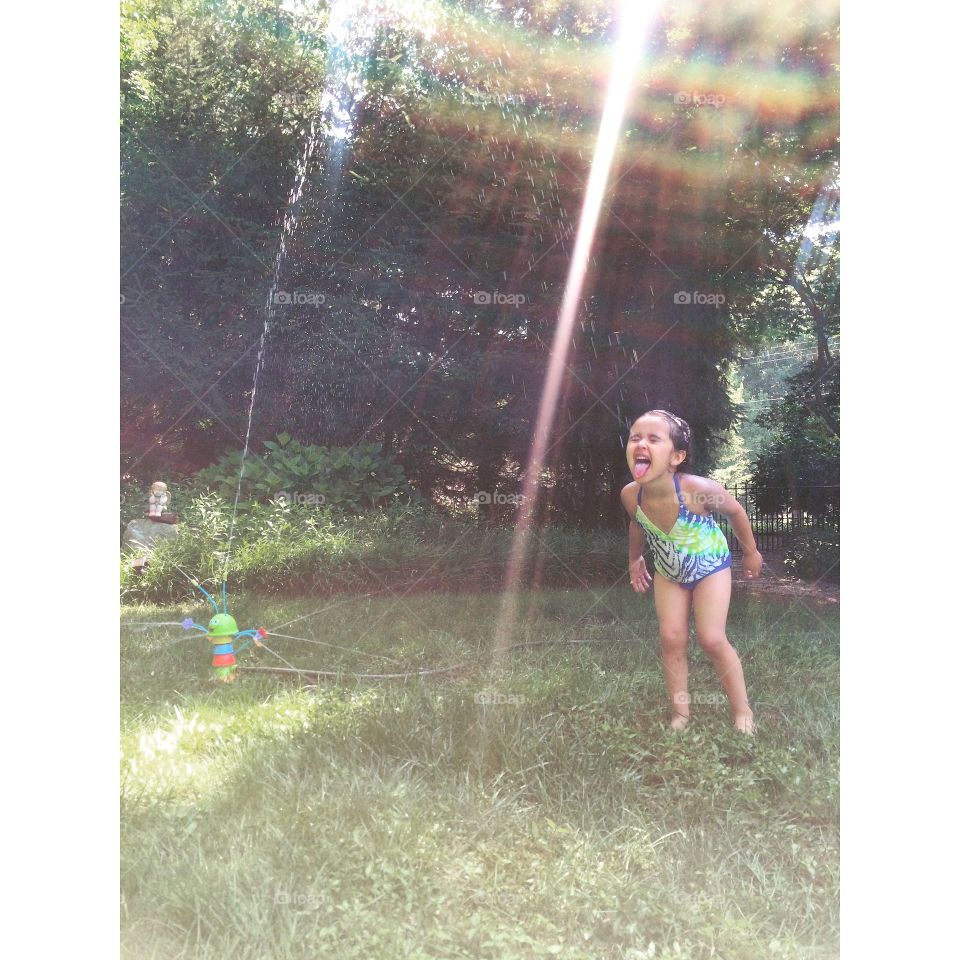 Little girl and water sprinkler in the garden