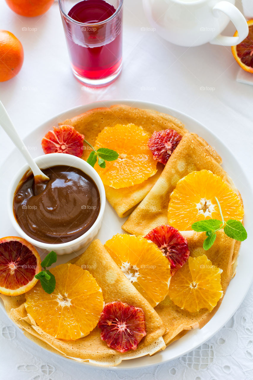 Crepes with oranges, chocolate sauce and nuts