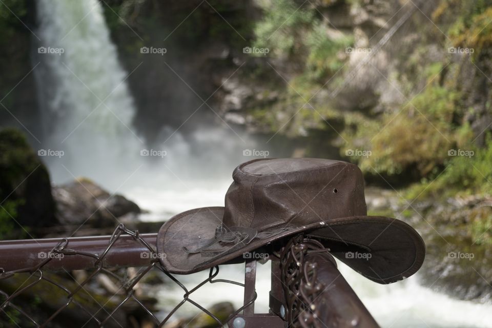 Remote waterfall in the Canadian Rocky Mountains leather cowboy hat on fence