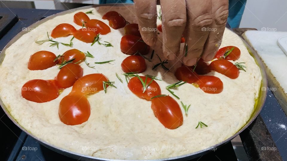 Putting cherry tomato in the pizza 