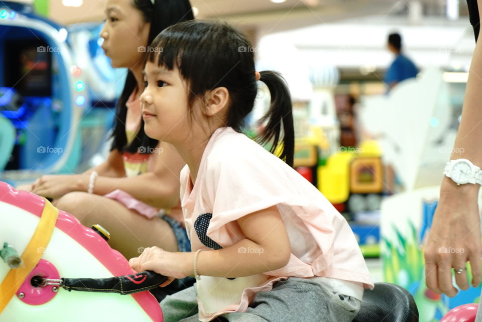 Asian girl riding on a game in Game Center 