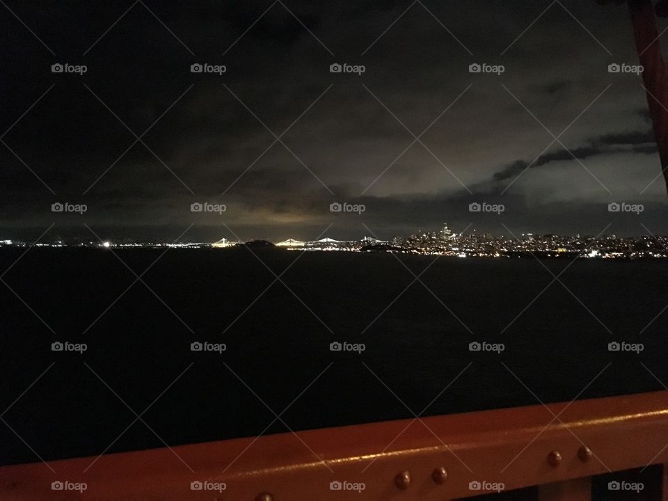 Lights of San Francisco at night from the Golden Gate Bridge, with the bay bridge lit up in the distance