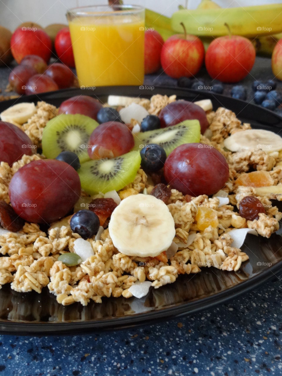 Healthy breakfast of crunchy flakes kiwi, banana, grapes, berries, raisins and fresh orange juicy drink