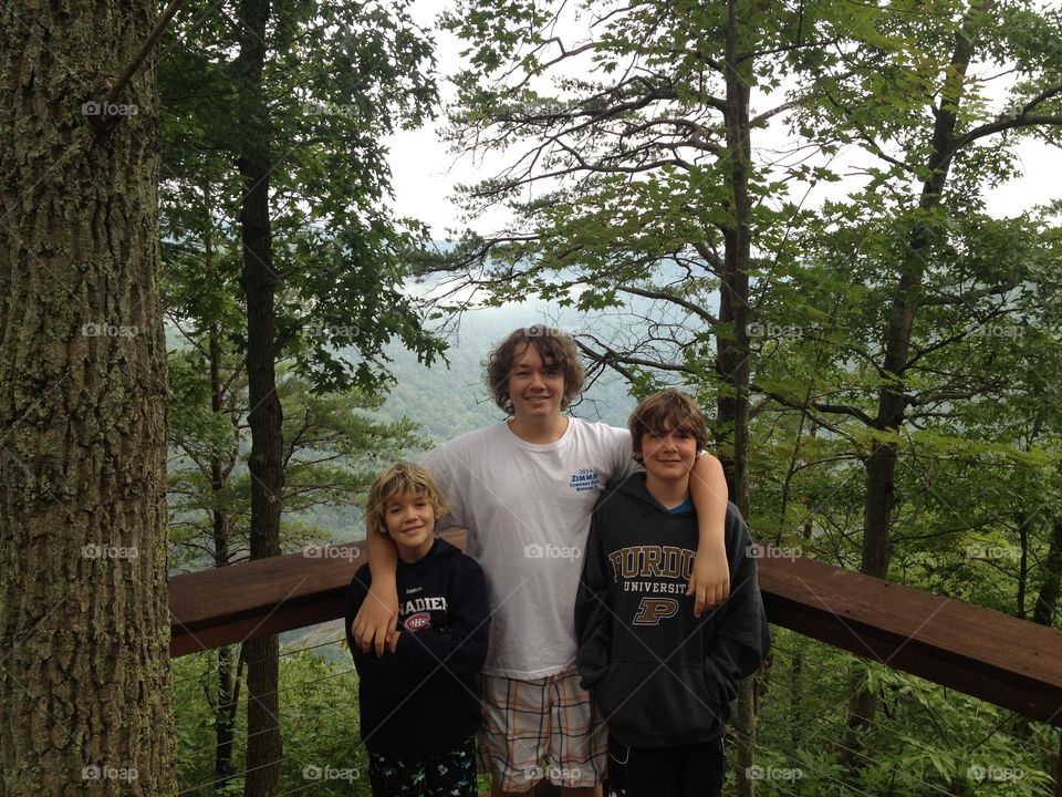 Portrait of happy brother standing near trees