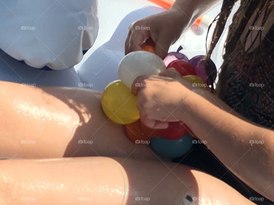 Child tying balloon. Child tying water balloon in swimming pool