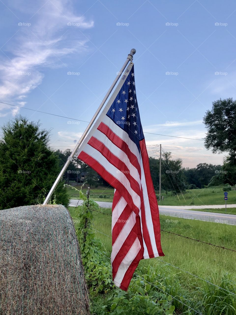 US flag mounted on hay bale in American countryside 