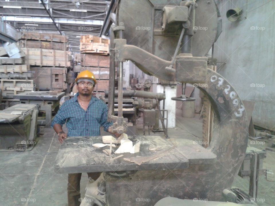 indian worker marking train parts in factory.
