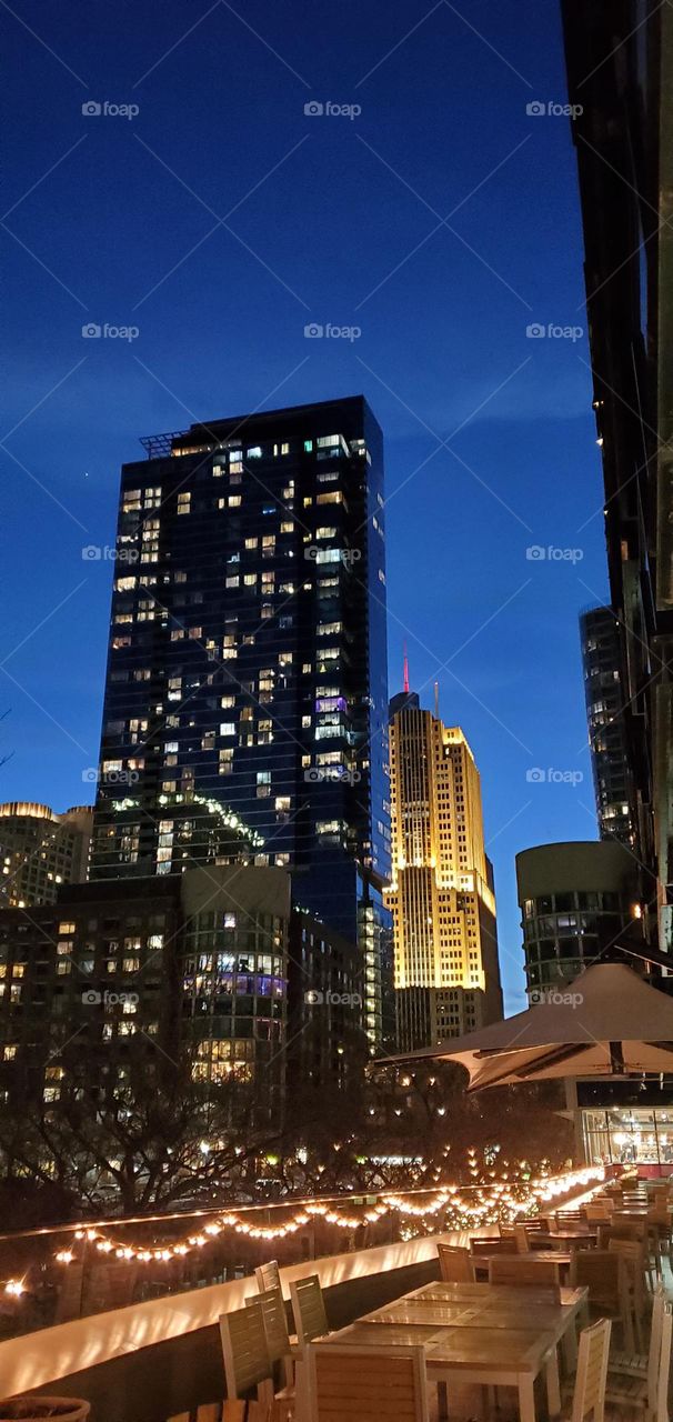 A highrise building towering over some smaller buildings behind it.
