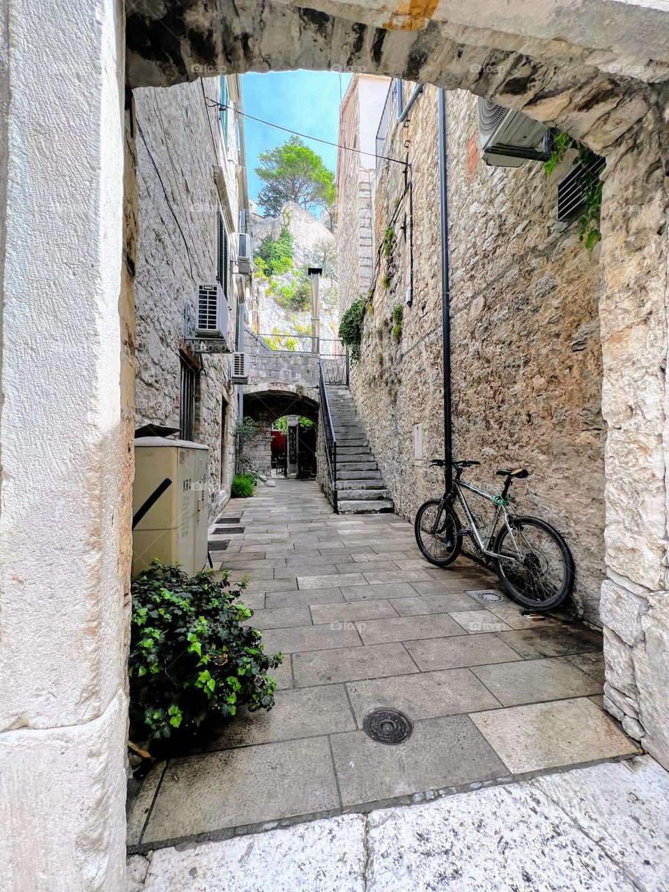 One lonely bicycle in the old city narrow alley between stone buildings 