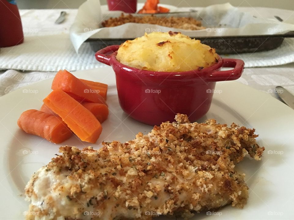 Gluten free chicken tenders with steamed carrots and baked potato pudding; plated at table