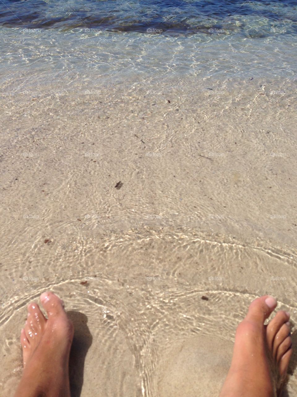 Feet on the sea transparent water and sunny day