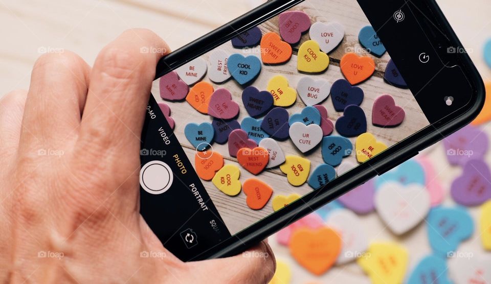 Taking photos to sell online with phone, woman’s hand holding phone and focusing, hearts scene shot digitally to sell online, photography sold online, Foap app sales, selling photos with a smartphone