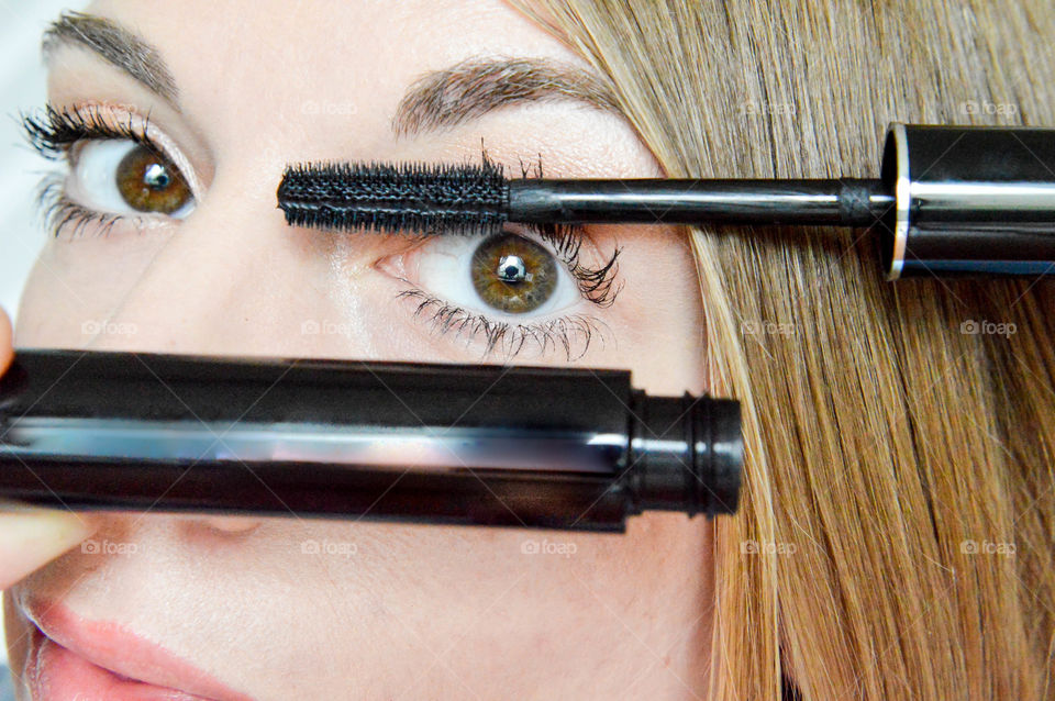 Close-up of a woman's eye while applying mascara