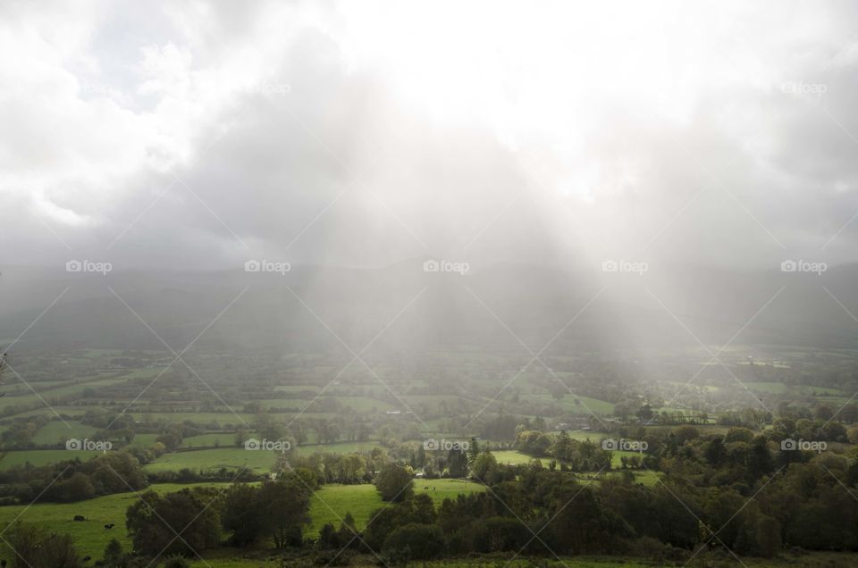 Sunbeams streaming down from above lightening the green pastures below after a thunderstorm!