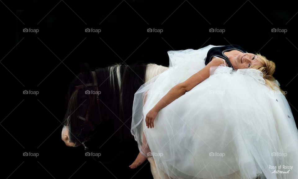 Woman lying on her horse wearing a wedding dress.