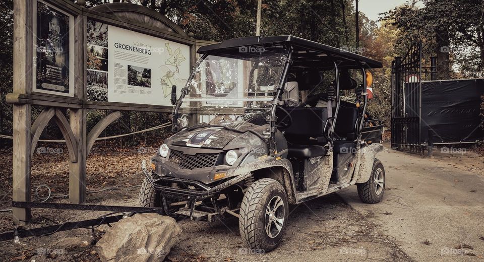 Dark gray vintage dirty electric hunting buggy parked in a private area of a public park in the woods after a hunt, close-up side view. The concept of hunting transport.
