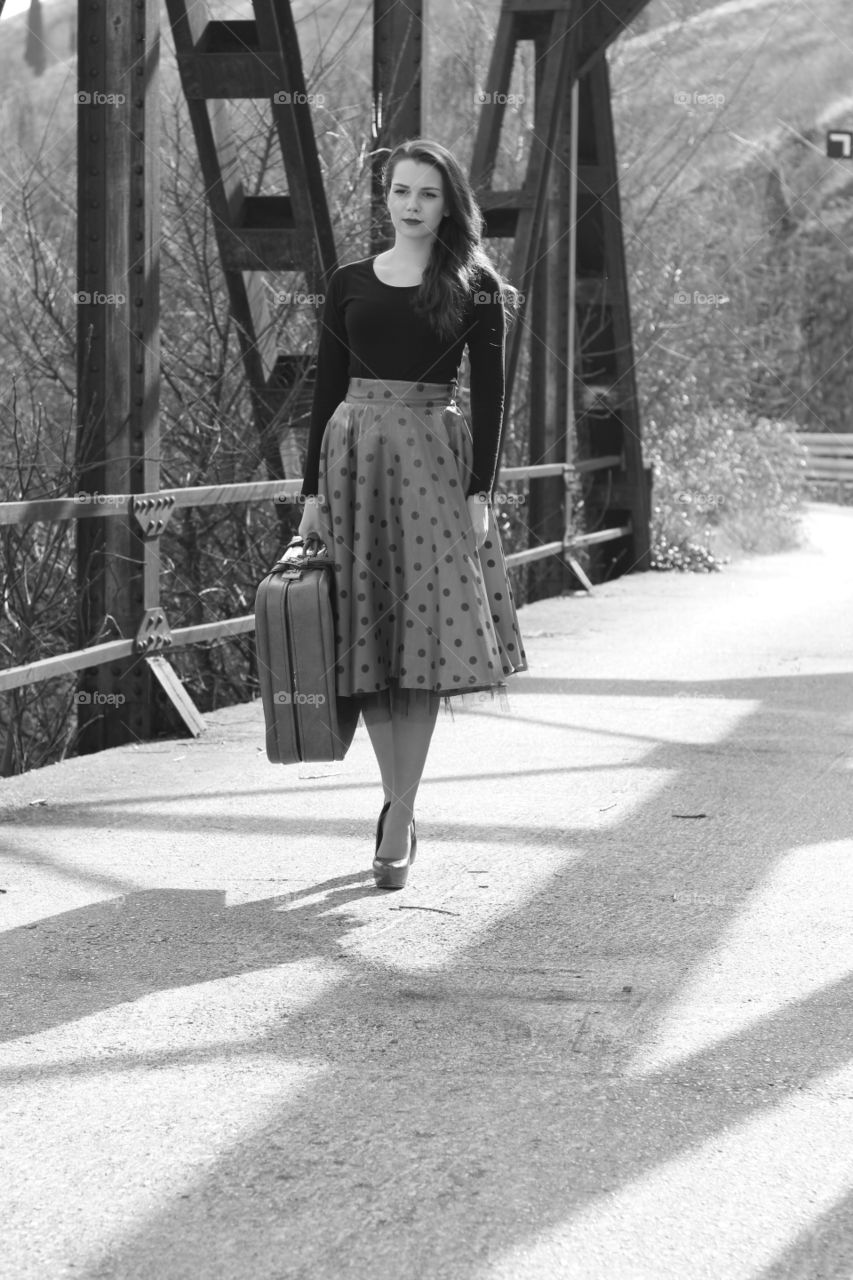 Beautiful woman walking on bridge with suitcase in hand