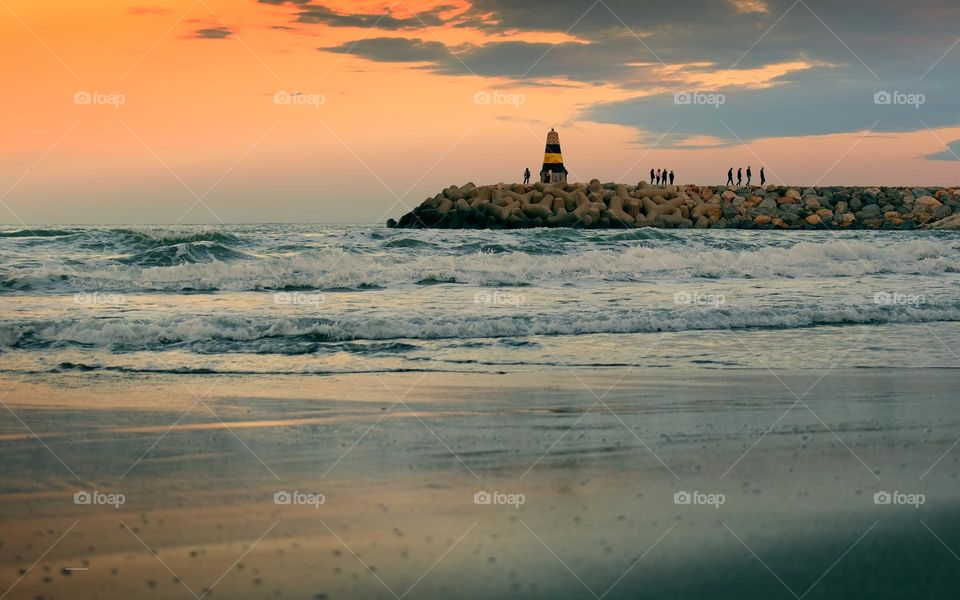 Sunrise scenery of sandy beach and lighthouse at Banalmadena, Malaga, Spain