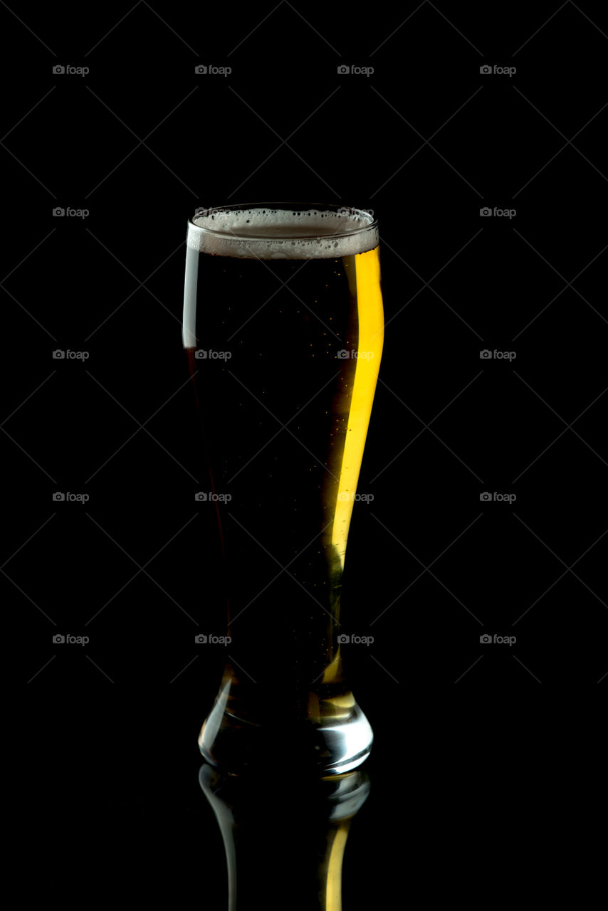 glass of golden beer isolated on black background