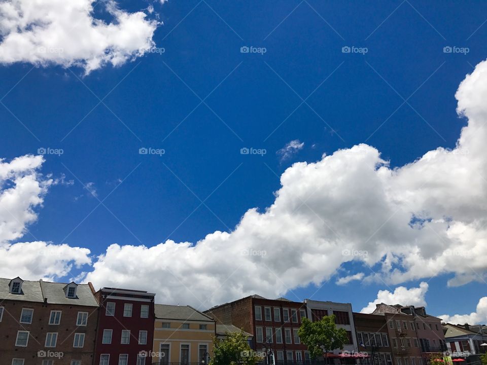 Skyline pops on a vivid blue puffy cloud background of French Quarter in New Orleans. 