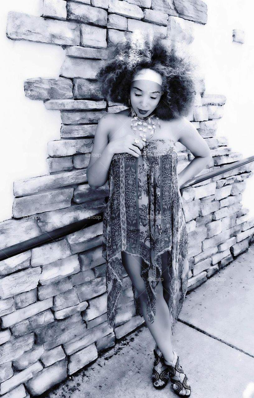 black and white fashion model posing against a brick wall