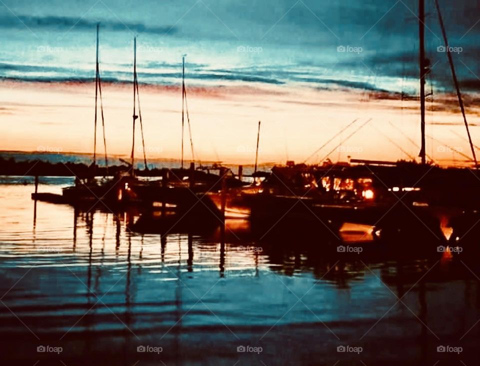 Silhouettes of the boats docked on the harbor as the sun sets