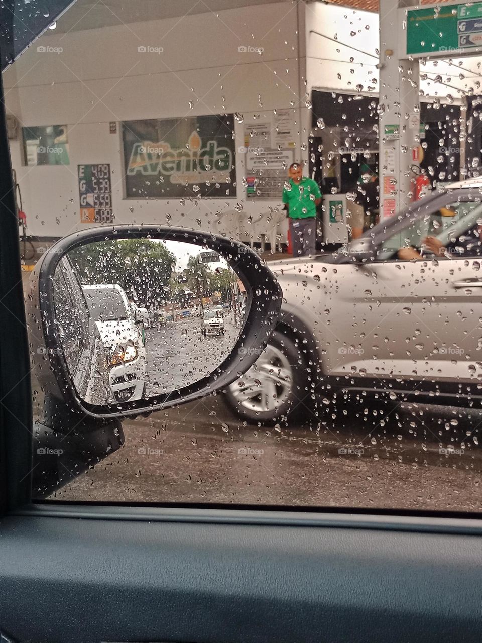 From inside a car on a rainy afternoon near a gas station