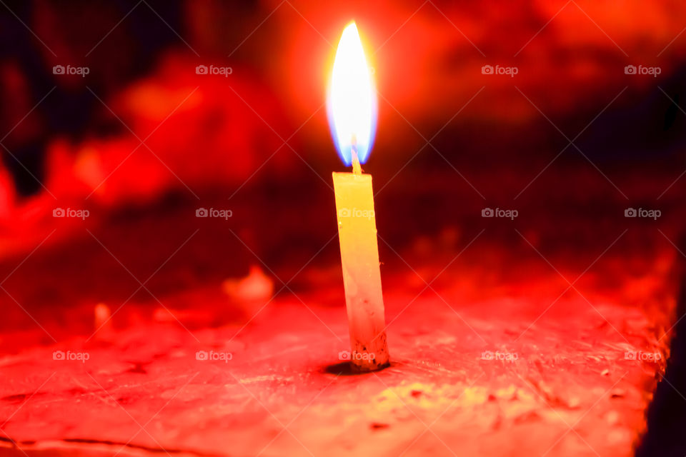 A Hanukkah candle spreading light on black background.