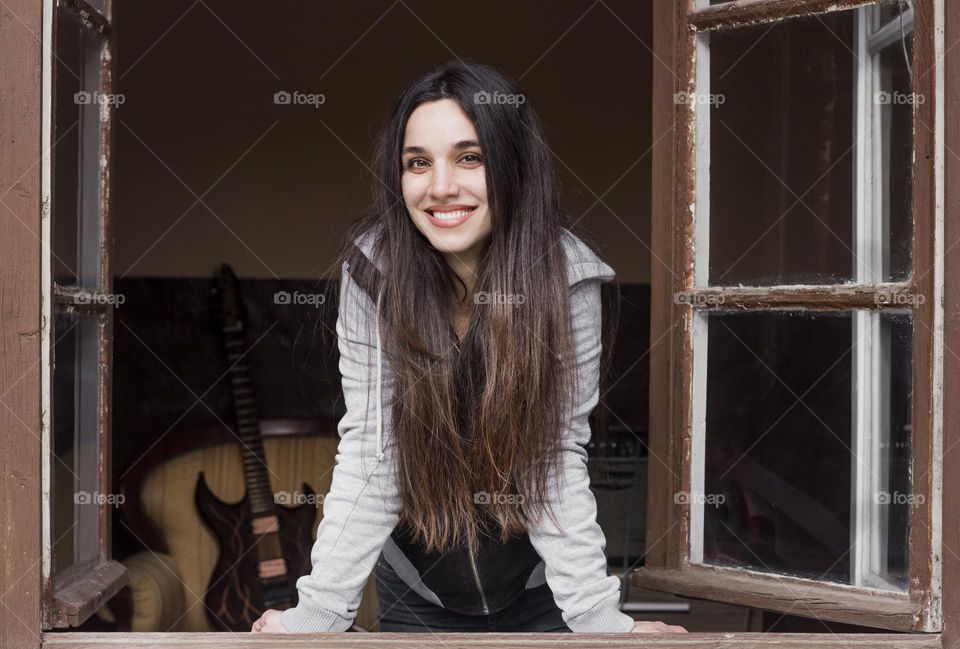 Smilong woman with long hair on the window