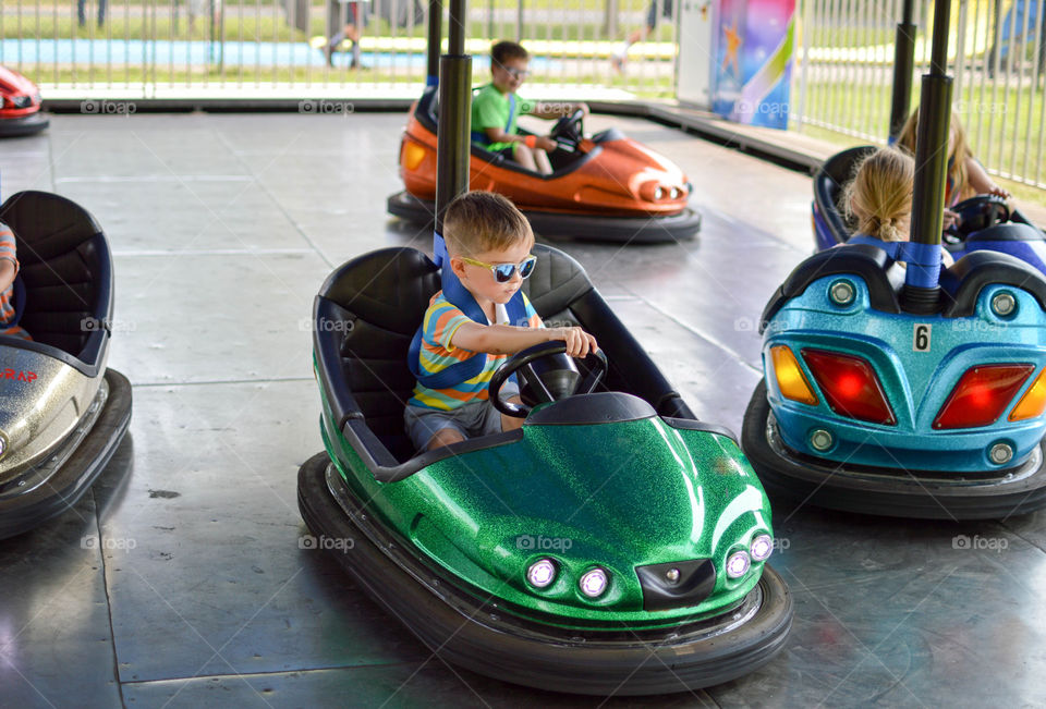 Young boy riding a bumper car at an amusement park on summer vacation