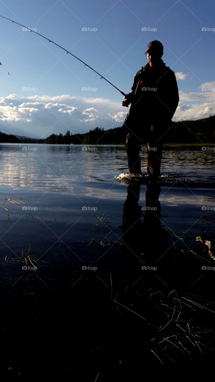 Fisher man holding fishing rod near lake