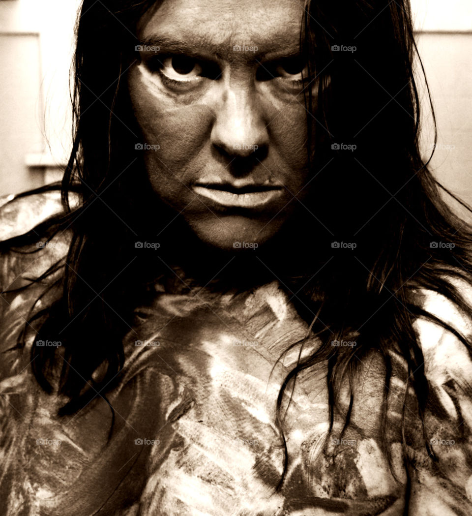 Mud. A woman covered in mud stares intensely at the camera