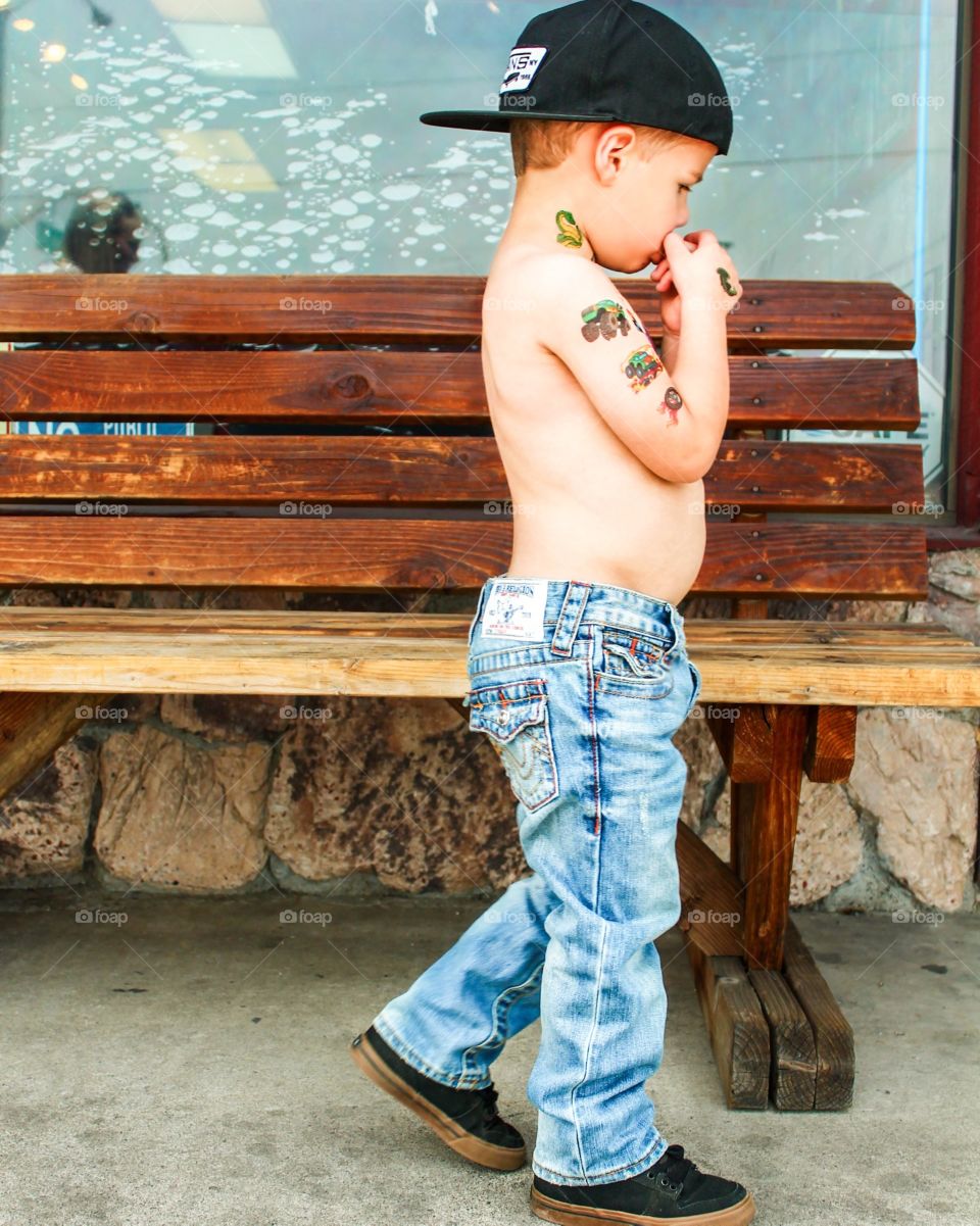 True Religion. Photo shoot with a little boy in his True Religion jeans. He's wearing fake tattoos at a tattoo parlor