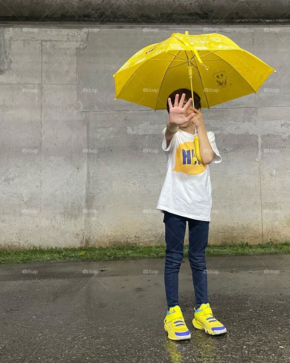 Rain day . Yellow umbrella and yellow shoes. Boy with umbrella. Stop raining 