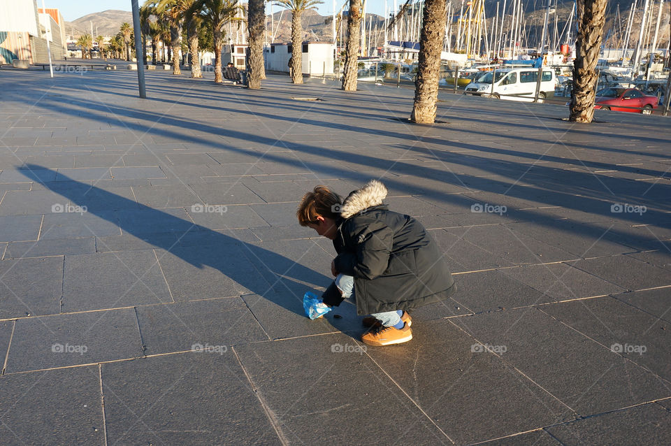 A boy cleaning his dog’s poo on the street
