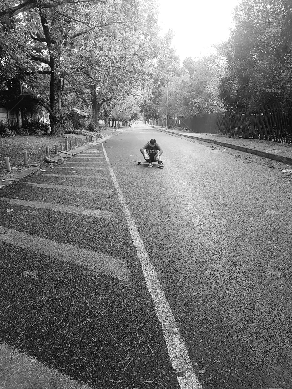 A beautiful picture of a skateboarder sitting in an iconic Jacaranda tree filled street in Johannesburg South Africa. The greyscale, simple yet effective in conveying the emotion this picture is meant to depict.
