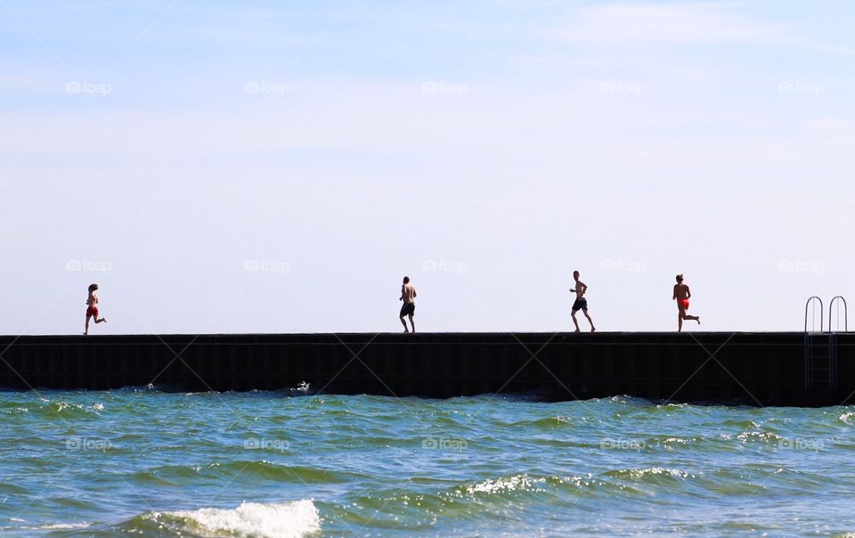 Run for water. People running on the jetty to swim