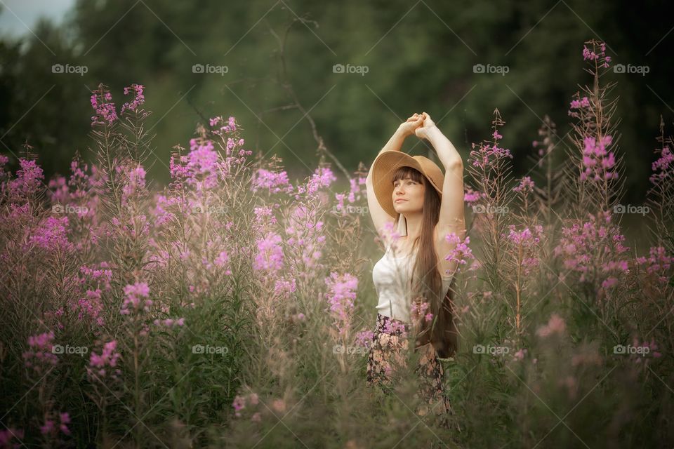 Beautiful young woman in a field of blossom flowers in boho style