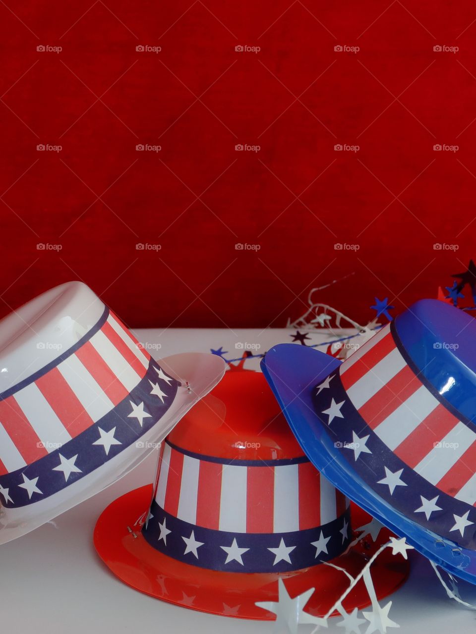 Tiny party hats in red, white, and blue with the Stars and Stripes for hat bands on a table with confetti. 