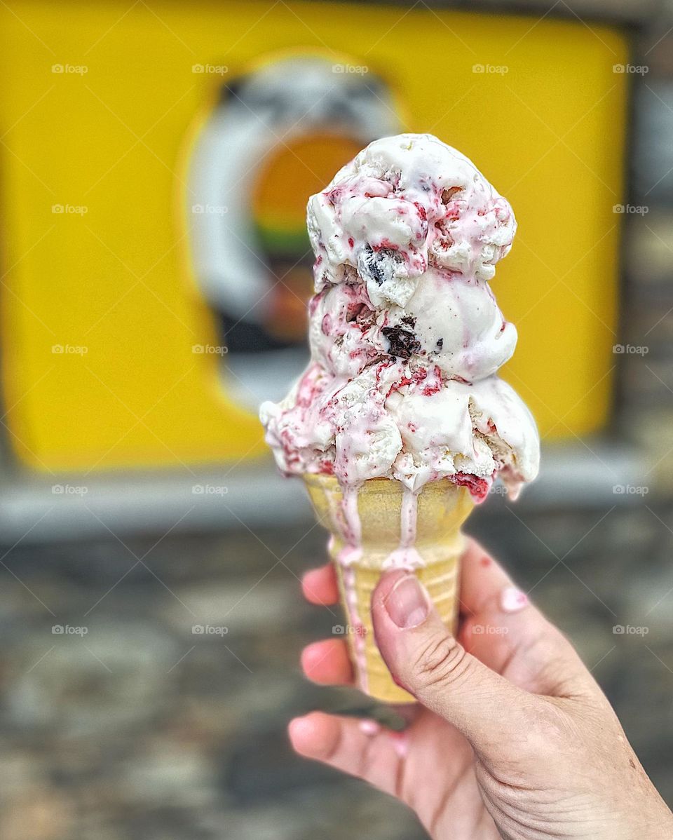 Woman holds ice cream cone as it drips onto hand, eating melting ice cream, ice cream on the beach, eating sweet desserts, delicious desserts on vacation
