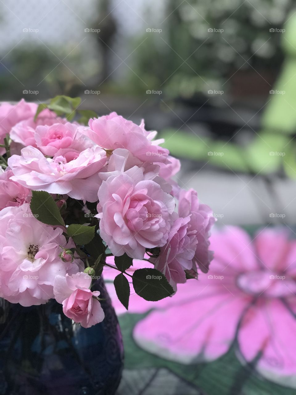 Sitting on my deck watching the golden sun set & admiring my deck garden. Some pale pink roses I cut from my overgrown rosebush make a beautiful center piece complementing the pink & green of my tablecloth & the green chair on my deck. 💖
