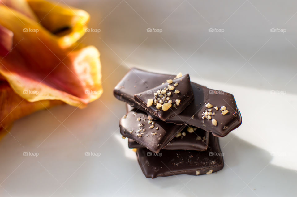 Stack of gourmet decadent dark chocolate covered crunchy caramel slabs with salted caramel salt crystal decoration in a pile on white platter epicurean chocolate background