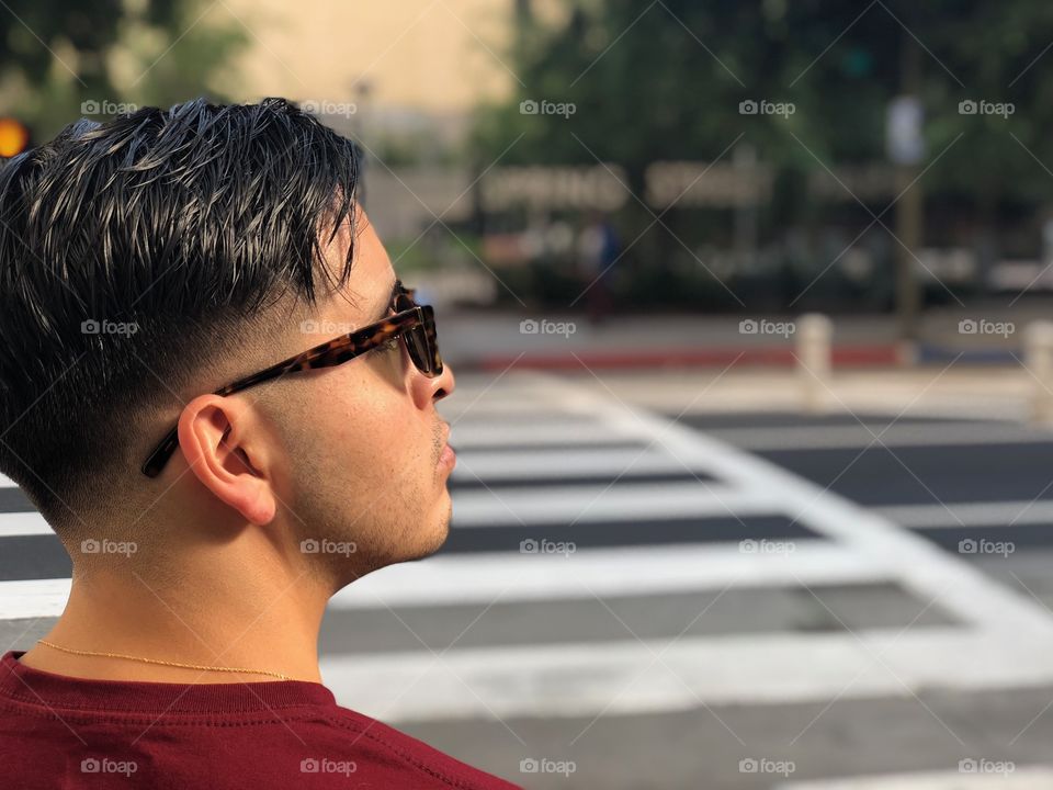 Young male wearing sunglasses looking to his right before crossing the street on DTLA.
