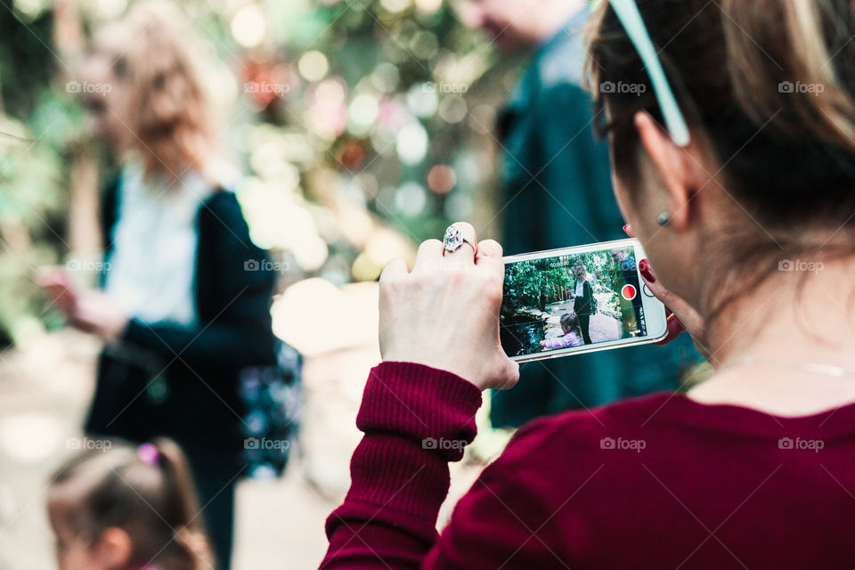 Young woman holding smartphone, looking at phone screen, recording a family trip