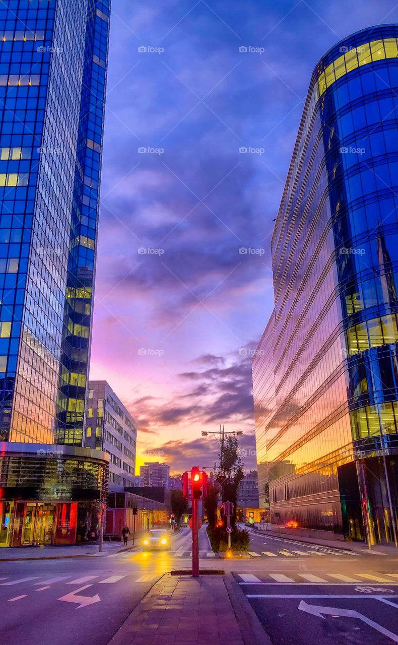 Colorful morning sky over the city streets, reflected in the glass windows of the office buildings of the business district of Brussels 